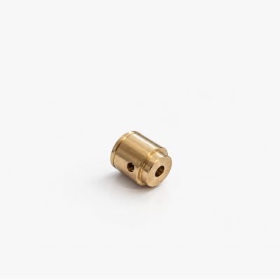 Small brass machined cylindrical fitting with a hollow center and side through hole, likely a bushing or spacer for mechanical assemblies.