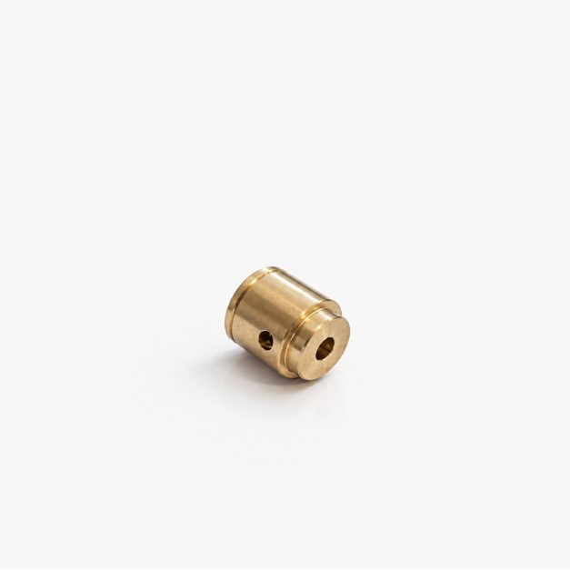 Small brass machined cylindrical fitting with a hollow center and side through hole, likely a bushing or spacer for mechanical assemblies.